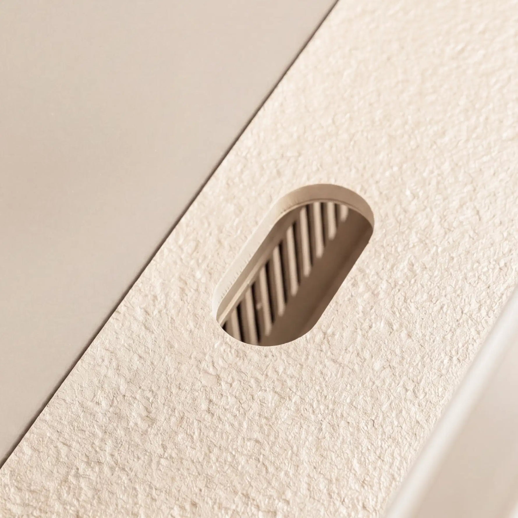 Détail du passe-câble intégré au plan de travail en céramique blanc Pilotis.
::visuel:creme