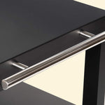 Gros plan sur la barre de poignée en inox d’une desserte de plancha noire, fixée sur le côté du plateau supérieur.