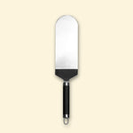 Grande spatule à poisson en inox avec manche noir, présentée sur fond beige.