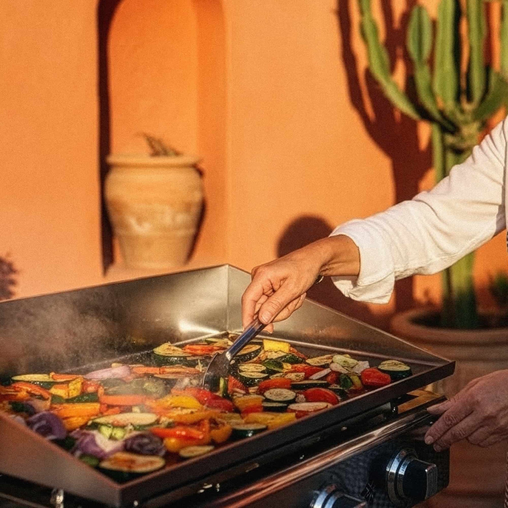 Koch bereitet Gemüse und Fleisch auf einer Vivaplancha Edelstahl-Plancha zu, beherrscht das Garen bei hoher Temperatur